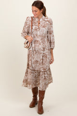 woman wearing a brown floral print midi dress with puff sleeves and a tiered skirt, accessorized with a small crossbody bag