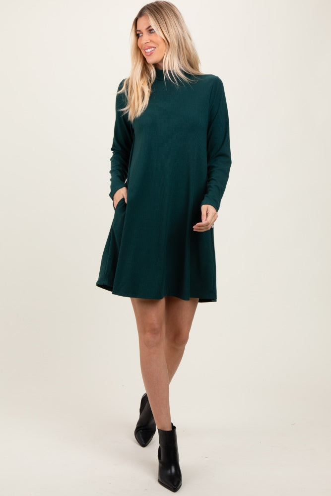 woman wearing a dark green long sleeve swing dress with pockets and ankle boots