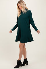 woman wearing a green long sleeve ribbed dress with a flared skirt and black ankle boots