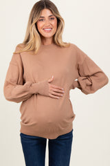 woman wearing a tan maternity sweater and holding her baby bump