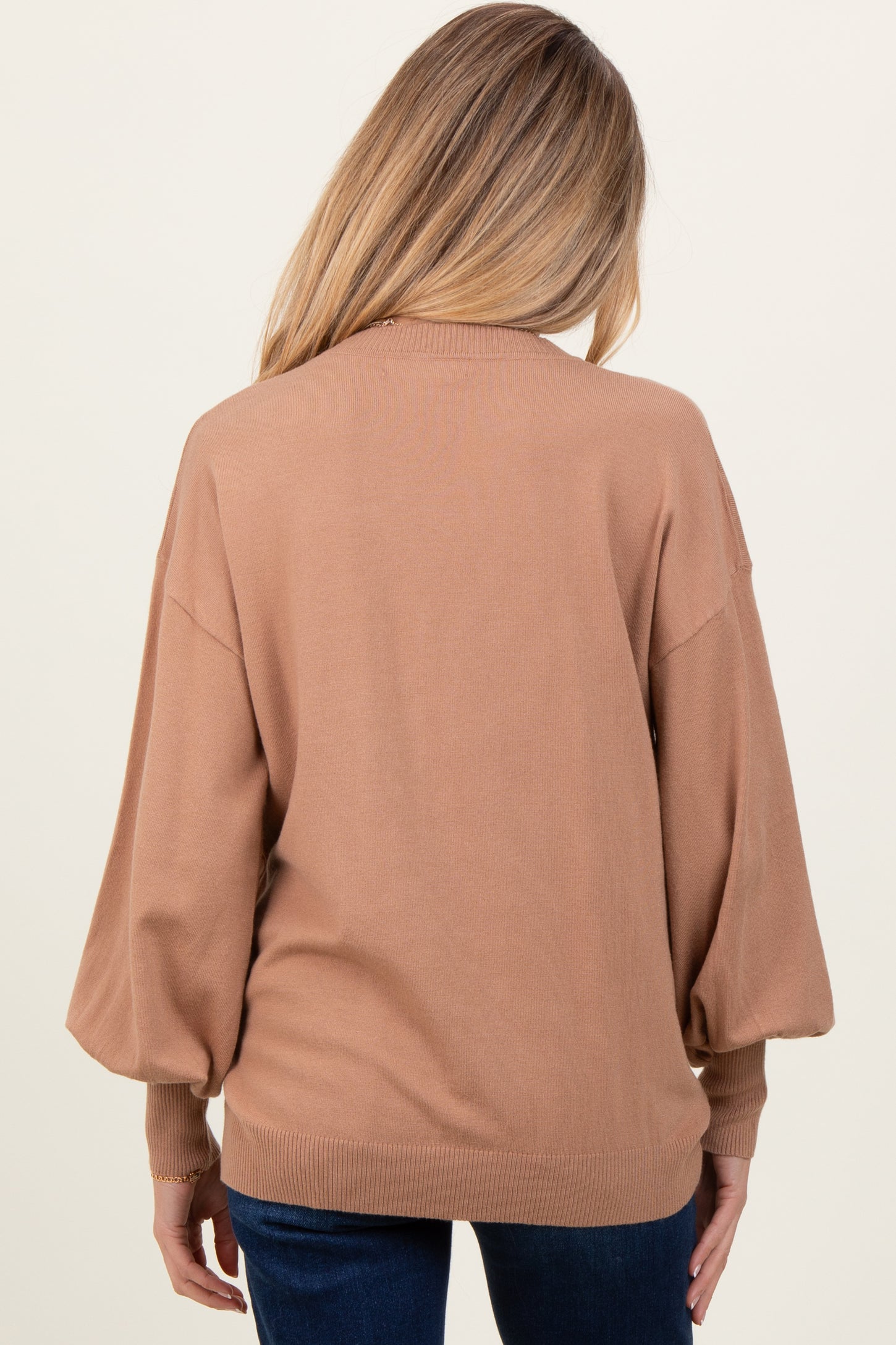 woman wearing a camel-colored oversized maternity sweater with balloon sleeves, viewed from the back