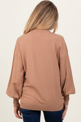 woman wearing a camel-colored oversized maternity sweater with balloon sleeves, viewed from the back