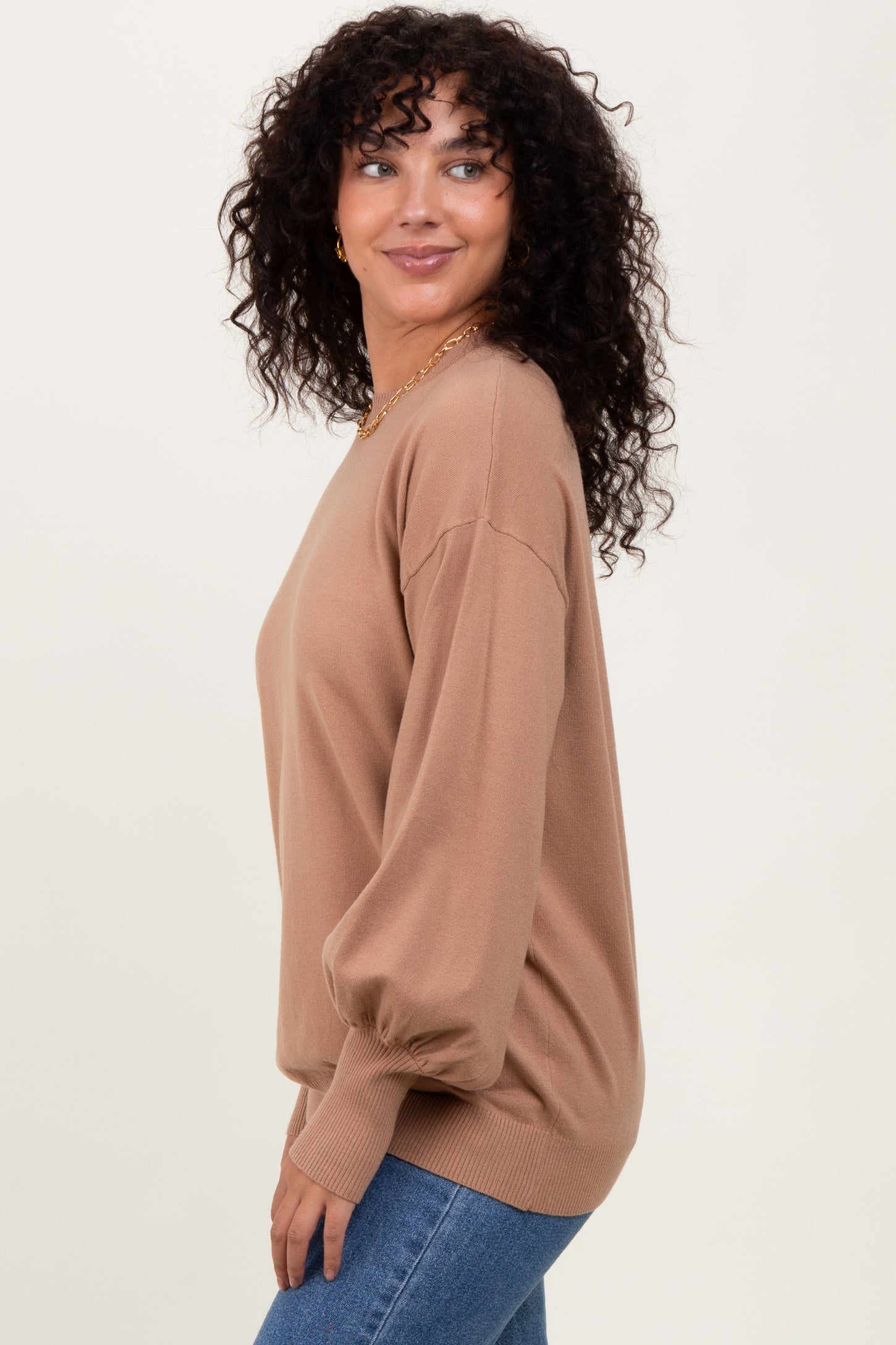 woman wearing a camel oversized sweater with balloon sleeves and styled with blue jeans