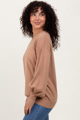 woman wearing a camel oversized sweater with balloon sleeves and styled with blue jeans