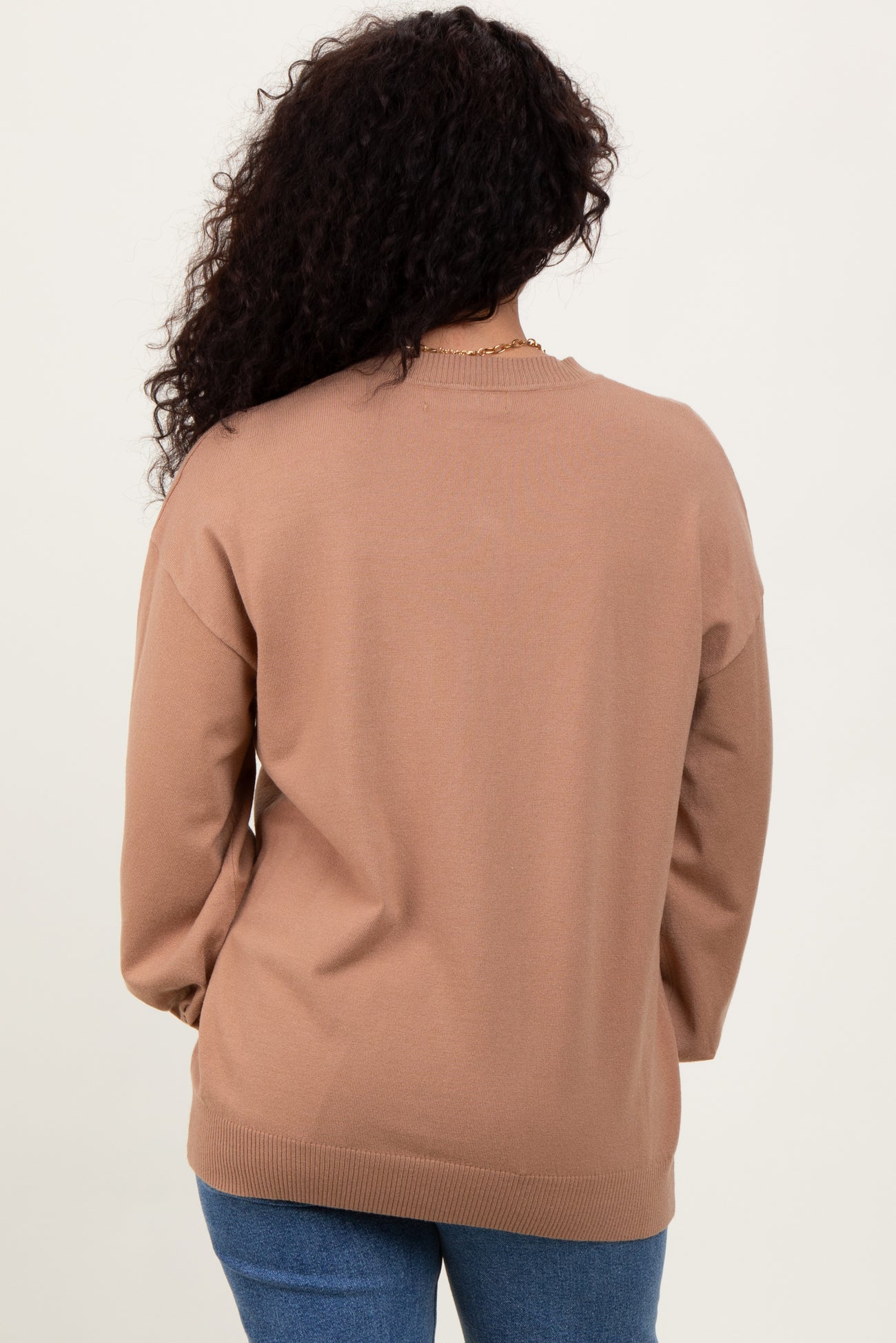 woman wearing a tan oversized sweater with long sleeves and a relaxed fit, shown from the back