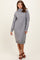 woman wearing a gray turtleneck sweater dress with side slits and long sleeves, styled with brown strappy sandals