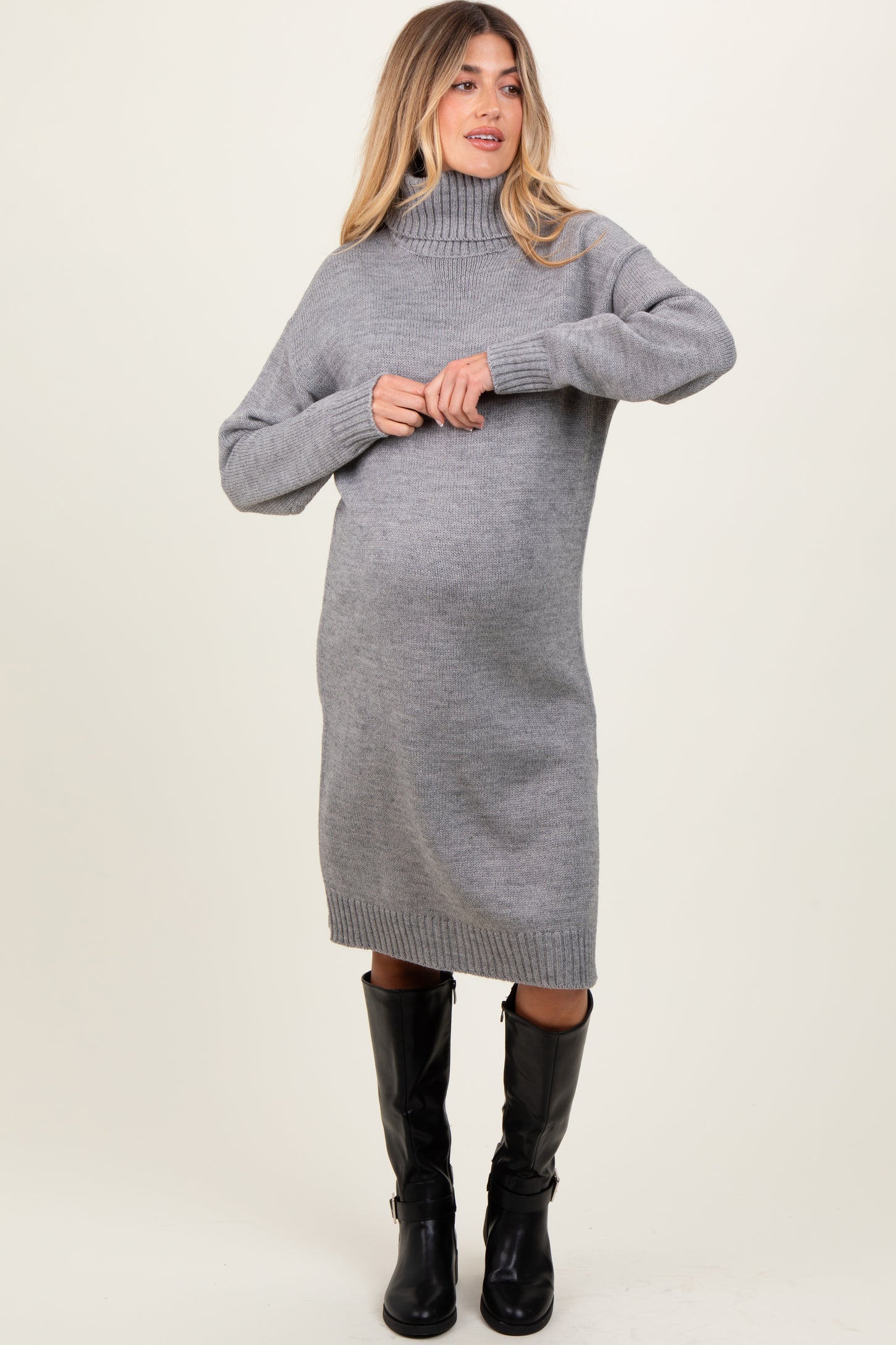 woman wearing a cozy gray turtleneck maternity sweater dress with a visible baby bump