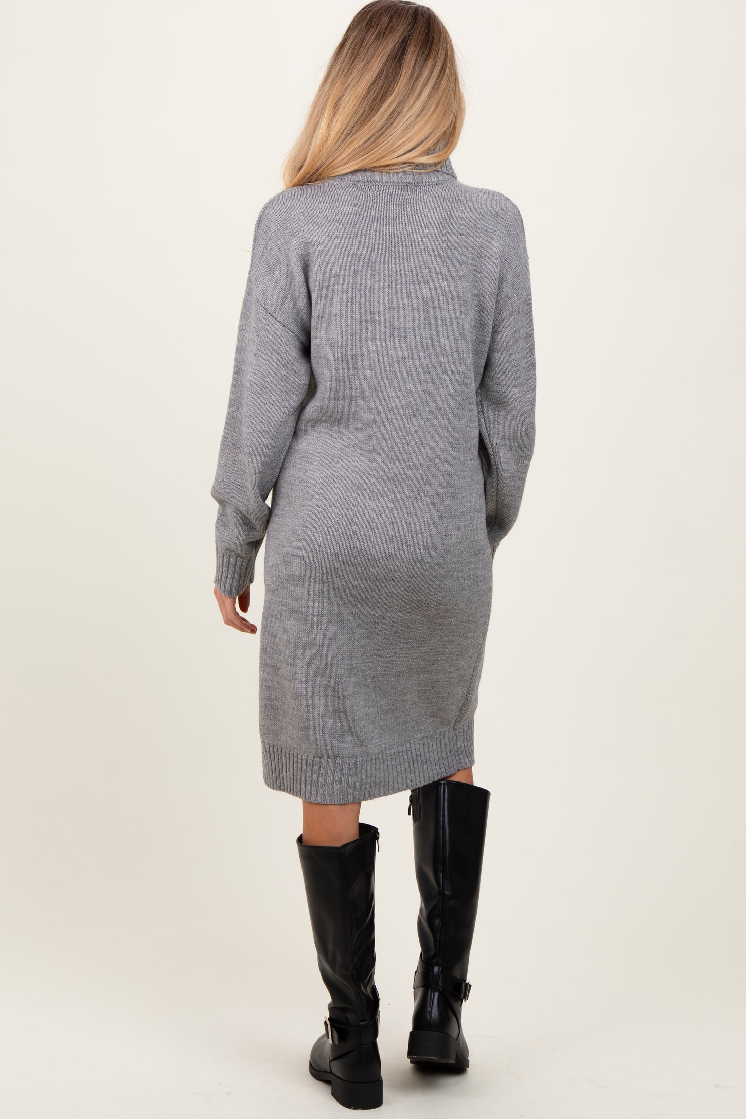 woman wearing a gray maternity sweater dress, standing with a relaxed fit and ribbed details, showing a baby bump from behind