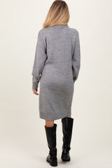 woman wearing a gray maternity sweater dress, standing with a relaxed fit and ribbed details, showing a baby bump from behind