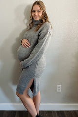 woman wearing a gray maternity sweater dress with turtleneck and side slits, showing her baby bump