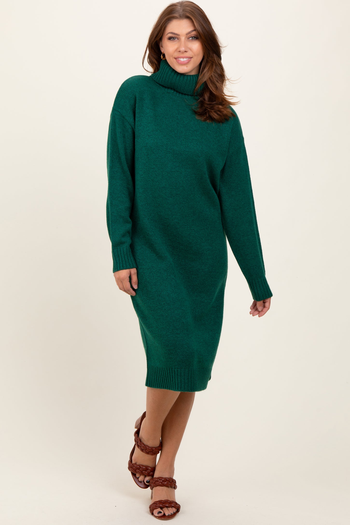 woman wearing a green turtleneck sweater dress with long sleeves and a relaxed fit, paired with brown strappy sandals