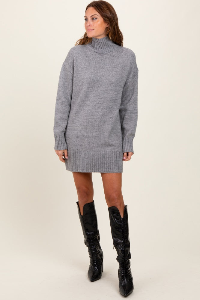 woman wearing a gray turtleneck sweater dress with ribbed cuffs and hem, paired with knee-high black boots