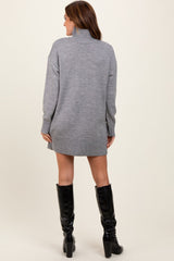 woman wearing a grey oversized sweater dress with a high neck and ribbed hem, paired with black knee-high boots