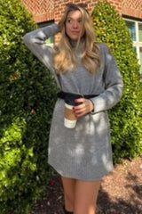 woman wearing a gray long sleeve belted sweater dress and holding a coffee cup
