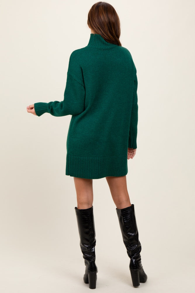 woman wearing a dark green oversized turtleneck sweater dress and black knee-high boots, seen from the back