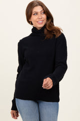 woman wearing a black cozy sweater with a high neckline and ribbed hem, paired with light blue jeans