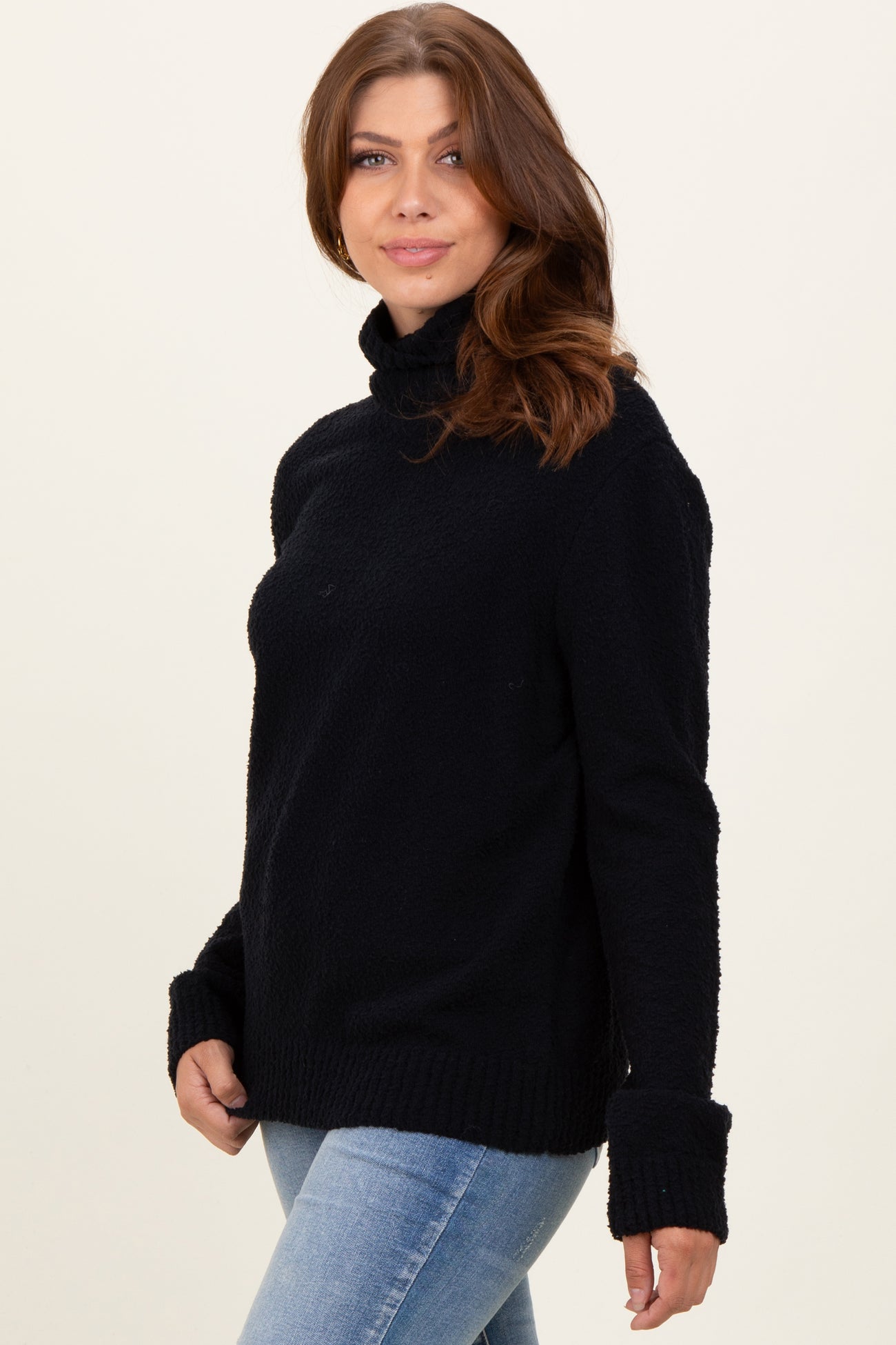 woman wearing a black cowl neck sweater with long sleeves and relaxed fit paired with light blue jeans
