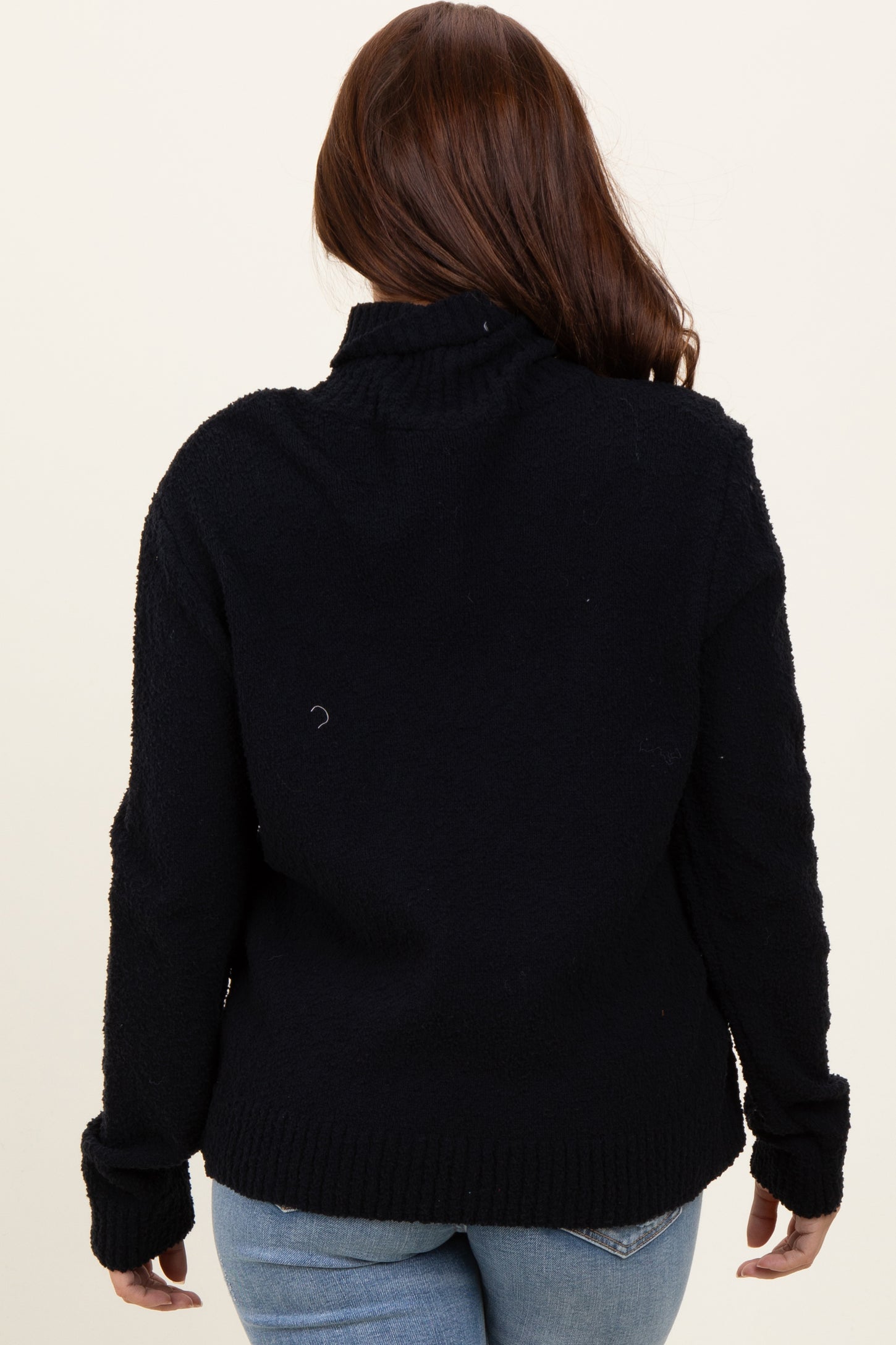 woman wearing a black fuzzy turtleneck sweater, viewed from the back, paired with light blue jeans