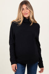 woman wearing a black turtleneck maternity sweater and showing her baby bump with a relaxed fit