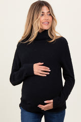 woman wearing a black maternity turtleneck sweater and holding her baby bump