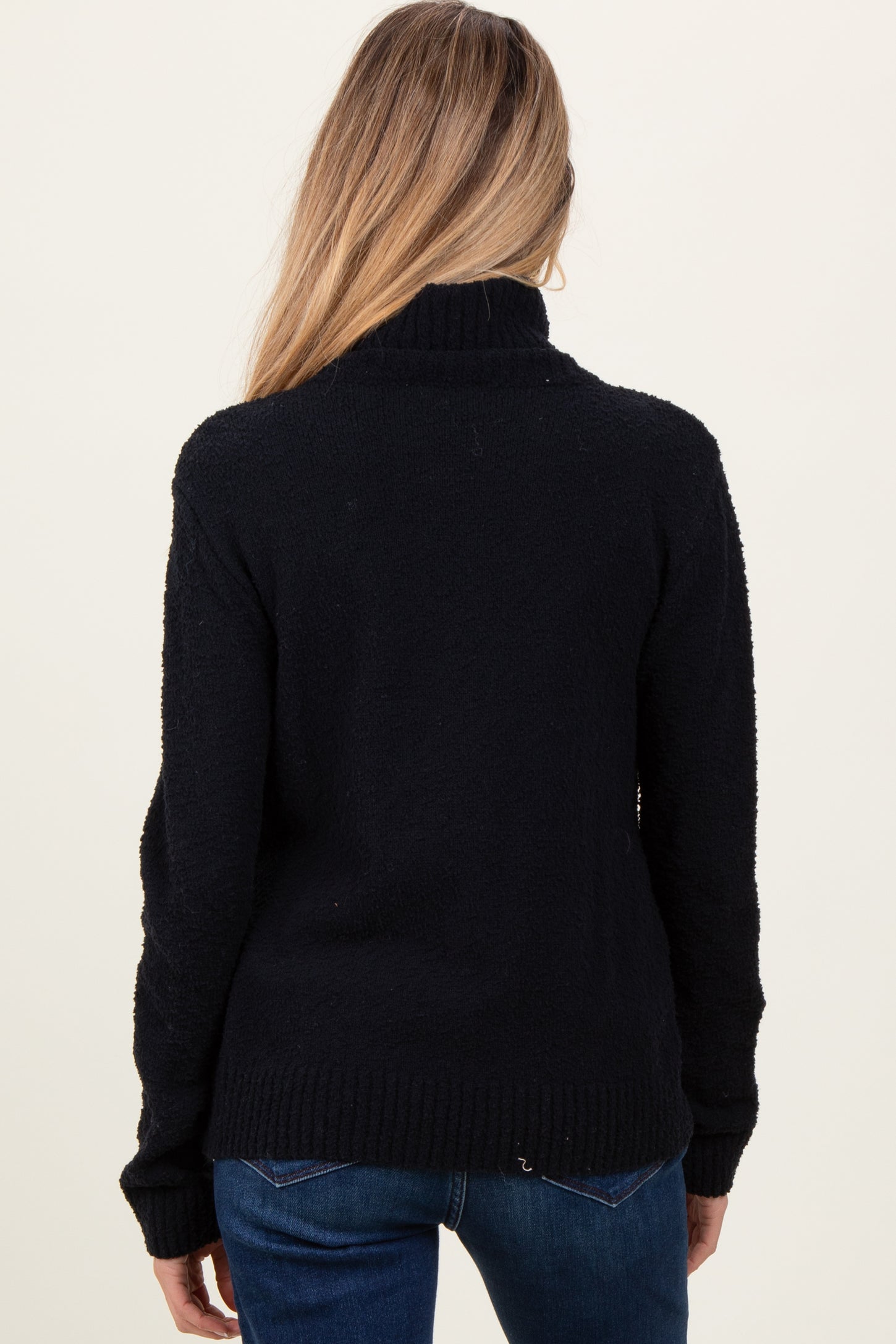 woman wearing a navy blue maternity sweater with a high neck and long sleeves, viewed from the back