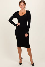 woman wearing a black ribbed long sleeve midi dress with a scoop neckline and posing elegantly