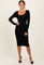 woman wearing a black ribbed long sleeve midi dress with a scoop neckline and posing elegantly