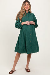 woman wearing a dark green long sleeve button-up maternity dress with a flared skirt and visible baby bump