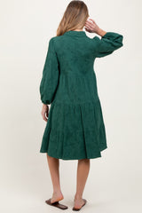 woman wearing a green maternity dress with tiered design and long sleeves, showing the back view