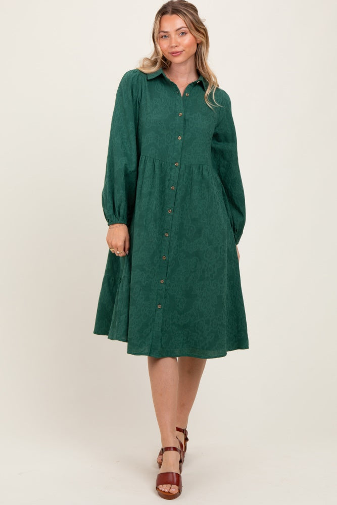woman wearing a dark green button-up dress with long sleeves and a flared skirt on a light background