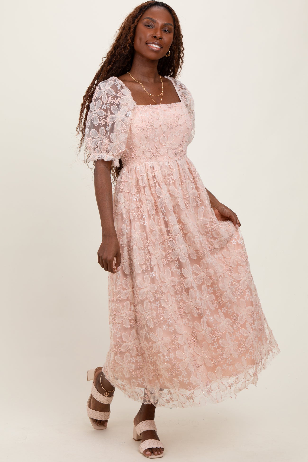 woman wearing a light pink floral lace maxi dress with puff sleeves and a square neckline