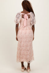 woman wearing a pink floral lace midi dress with puff sleeves and a bow detail at the back