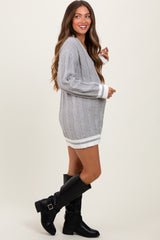 woman wearing a light grey cable knit maternity sweater dress with white trim and black knee-high boots