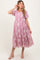 woman wearing a pink floral embroidered maternity dress with puff sleeves and a tiered skirt, showing a baby bump
