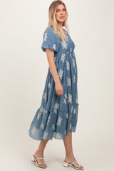 woman wearing a blue floral embroidered maxi dress with puff sleeves and a tiered skirt