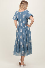woman wearing a blue floral midi dress with short puff sleeves and a tiered skirt, shown from the back