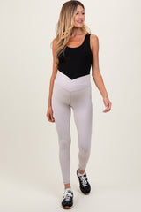 woman wearing a black and cream maternity bodysuit with high-waisted beige leggings, showing a baby bump