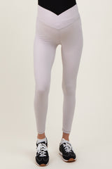 woman wearing light gray maternity leggings with a high waistband and a sleek fit