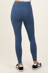 woman wearing blue high-waisted leggings, showing the back view with black and white athletic shoes
