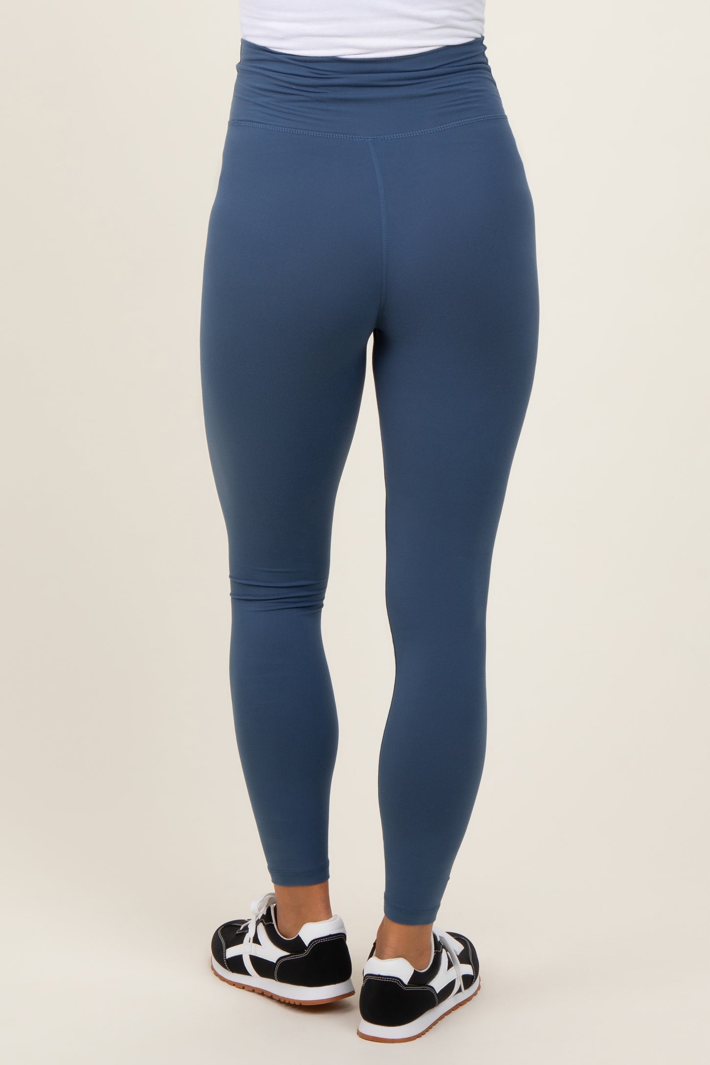 woman wearing blue maternity leggings, shown from the back with a high waistband and a fitted style