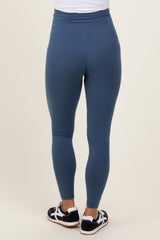 woman wearing blue maternity leggings, shown from the back with a high waistband and a fitted style
