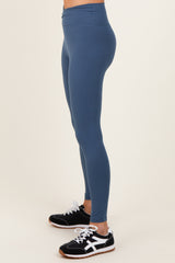 woman wearing blue high-waisted leggings and black athletic shoes, standing sideways