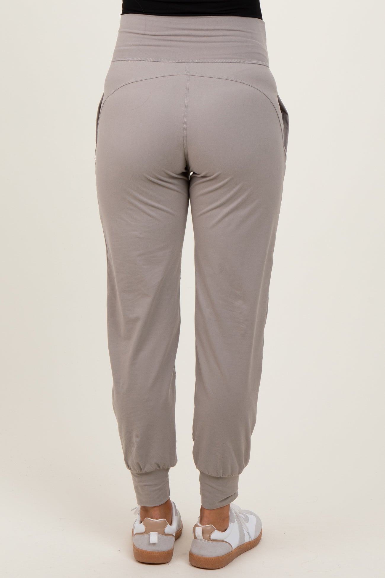 woman wearing light gray maternity joggers with elastic waistband and side pockets, view from the back
