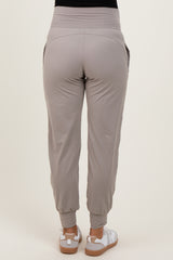 woman wearing light gray maternity joggers with elastic waistband and side pockets, view from the back