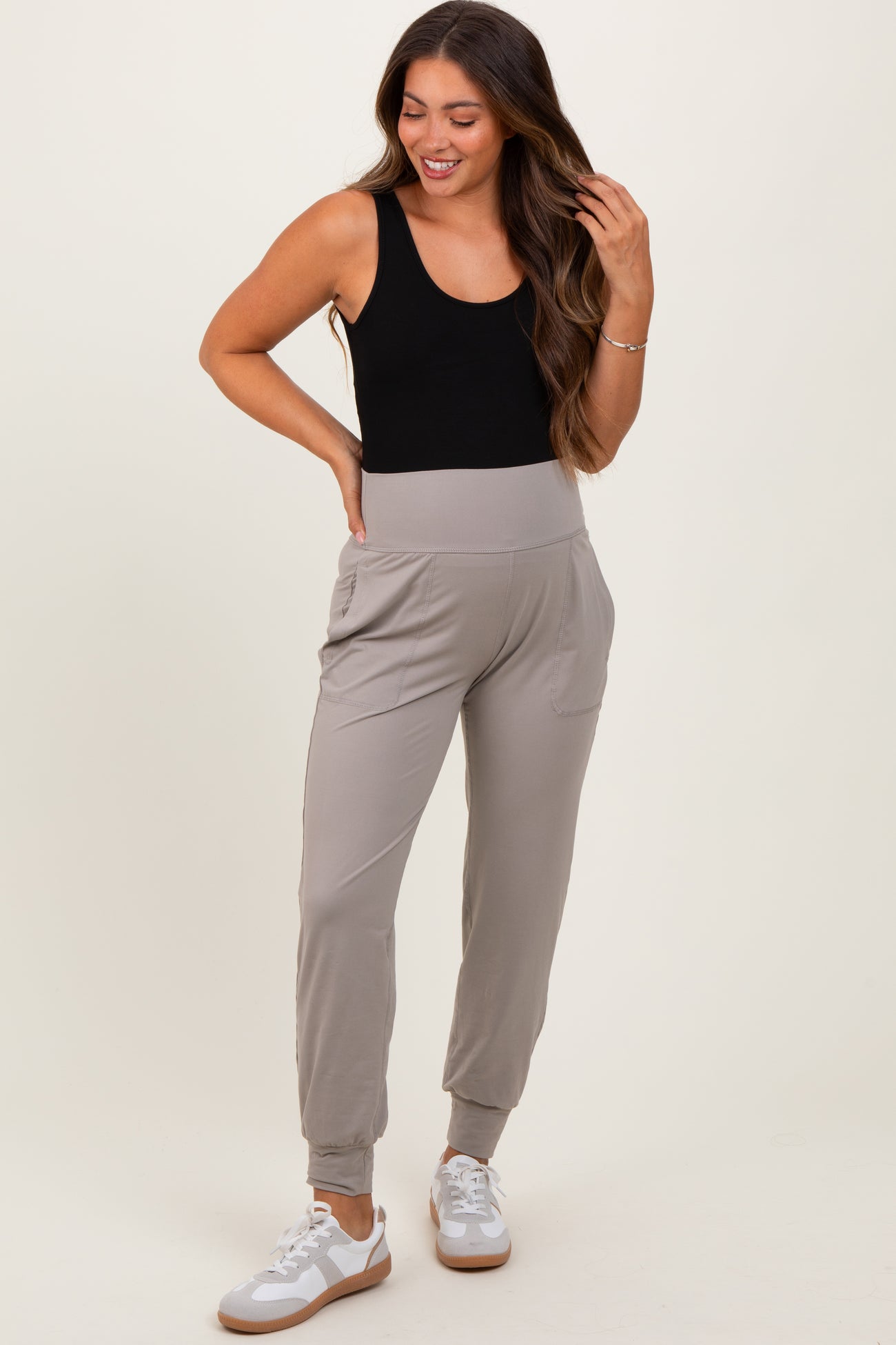 woman wearing a black tank top and grey maternity joggers with pockets, showing off her baby bump