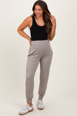 woman wearing a black tank top and grey maternity joggers with pockets, showing off her baby bump