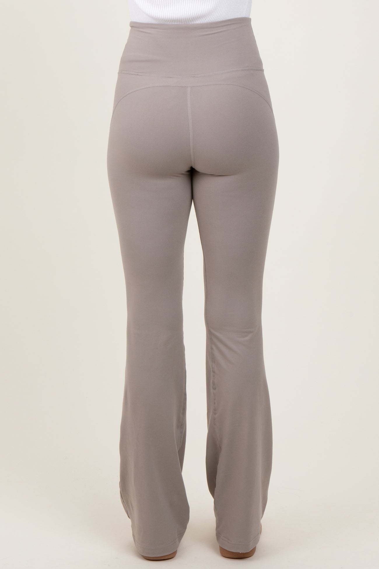 woman wearing high-waisted light brown flared leggings, view from the back