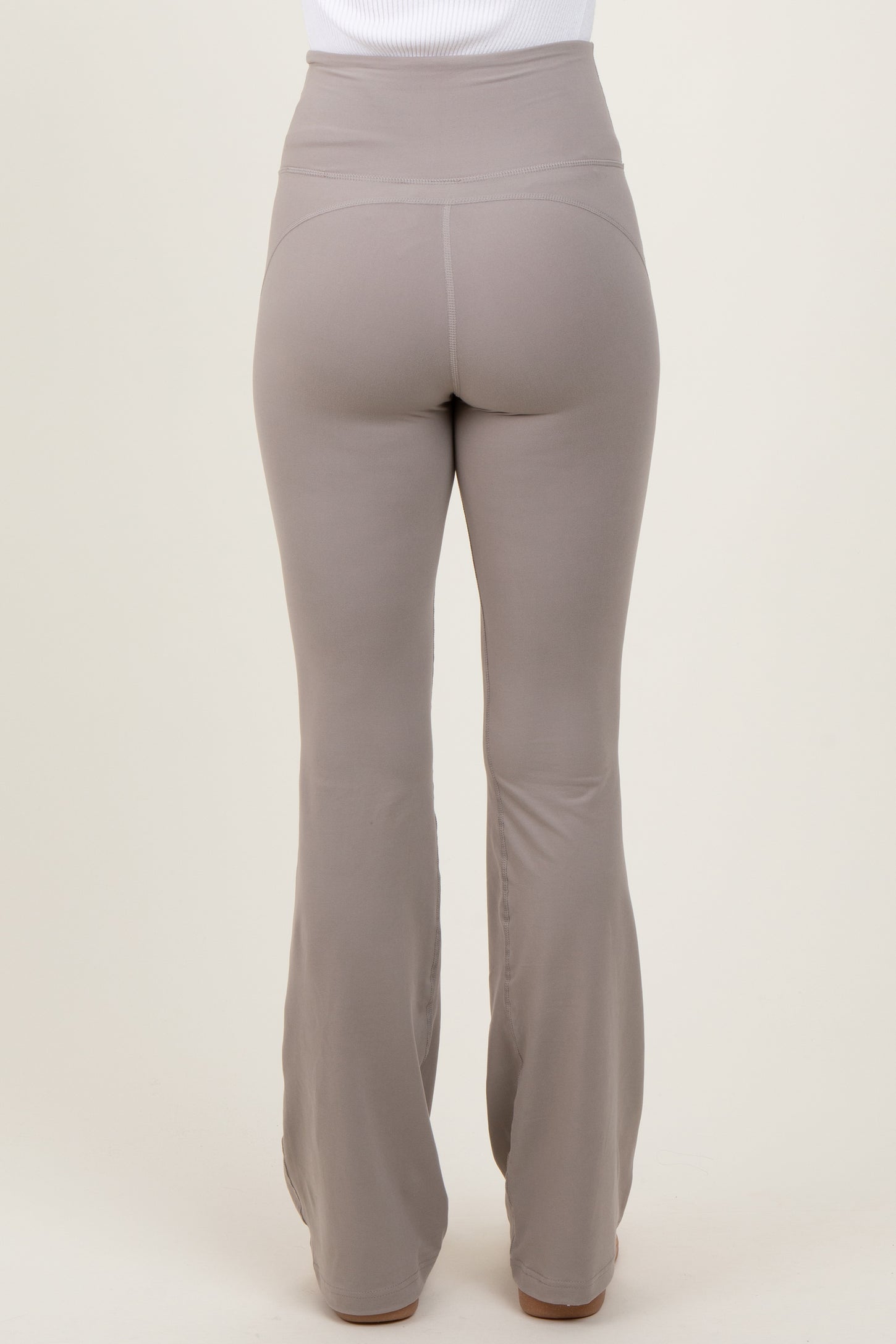woman wearing high-waisted light brown flared leggings, view from the back
