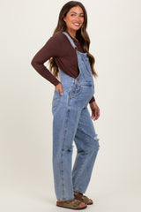 woman wearing a brown long sleeve maternity top and light blue distressed maternity overalls