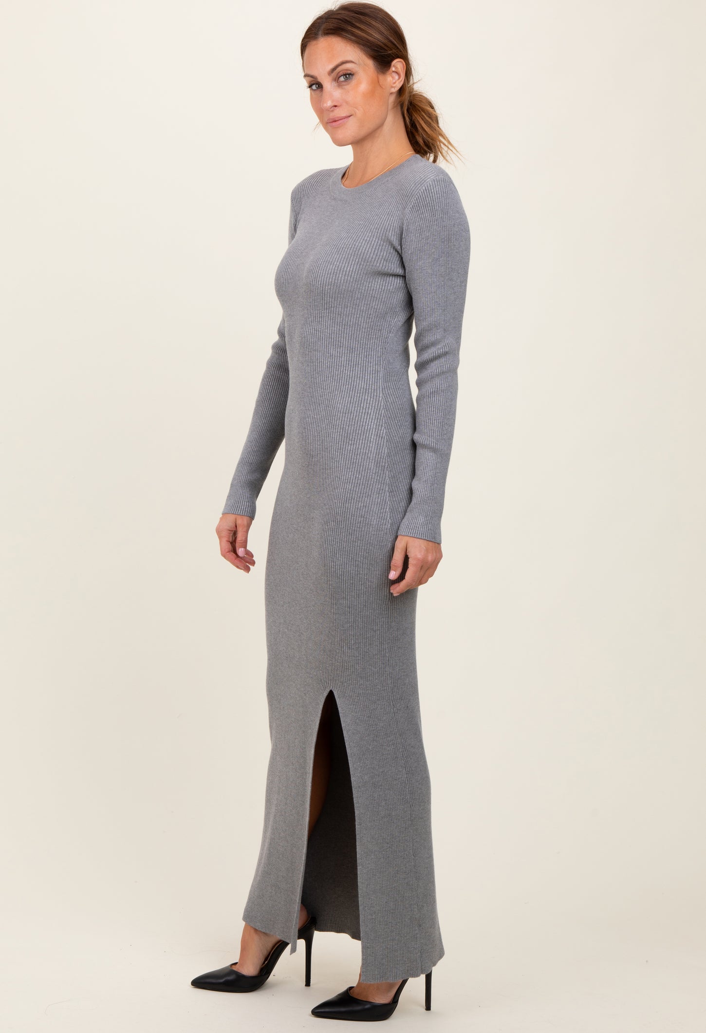 woman wearing a grey ribbed long sleeve maxi dress with a side slit and black heels